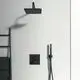 Schwarzer Duschkopf montiert an einer Wand, daneben ein Duschschlauch und ein Steuerpanel in Schwarz, beide Produkte von Ideal Standard. Im Hintergrund ein Handtuchhalter.
